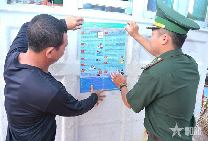 Bộ đội Biên phòng Đất Mũi hướng dẫn ngư dân treo các khẩu hiệu tuyên truyền pháp luật trên tàu.