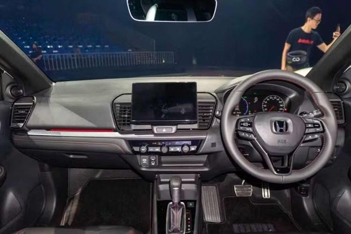 Nội thất của Honda City 2026 không thay đổi về bố cục và cấu hình, nhưng một số khu vực đã được nâng cấp. Mặt táp-lô trên bản RS sử dụng bề mặt trang trí màu bạc có họa tiết rõ hơn, kết hợp đường chỉ màu đỏ. Xe cũng được bổ sung đèn viền nội thất, màu đỏ trên bản RS và màu xanh trên bản V. Gương chiếu hậu bên ngoài cũng được bổ sung chức năng tự động gập.