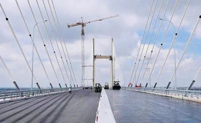 Công nhân khẩn trương hoàn thiện sơn vạch kẻ đường và hệ thống an toàn giao thông trên cầu Phước Khánh. Ảnh: DK