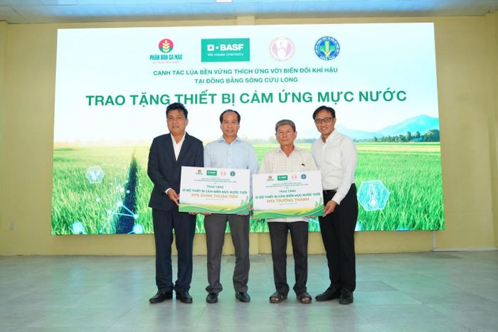 Đại diện các bên trao bảng tượng trưng thiết bị quản lý nước tưới ướt - khô xen kẽ (AWD) cho đại diện các hợp tác xã địa phương.