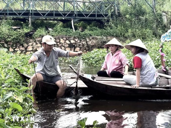 Du khách trải nghiệm cách dỡ lưới chài cá. (Ảnh: Hồng Nhung/TTXVN)