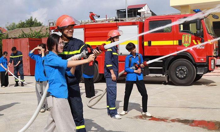 Học sinh, người dân trải nghiệm chữa cháy bằng lăng, vòi chữa cháy của lực lượng chức năng.