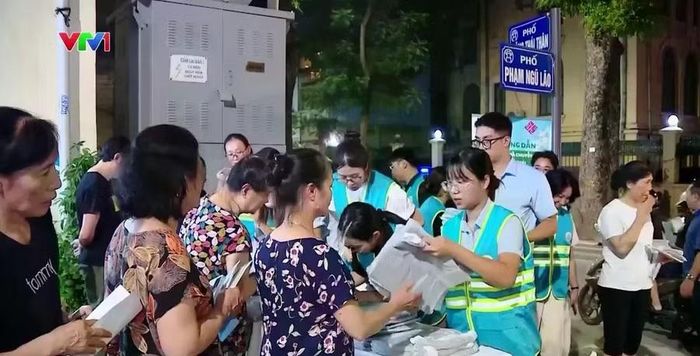 Nhân viên Công ty Môi trường đô thị Hà Nội phát túi đựng rác và tờ rơi hướng dẫn để người dân nắm rõ cách thức thực hiện. Ảnh: VTV
