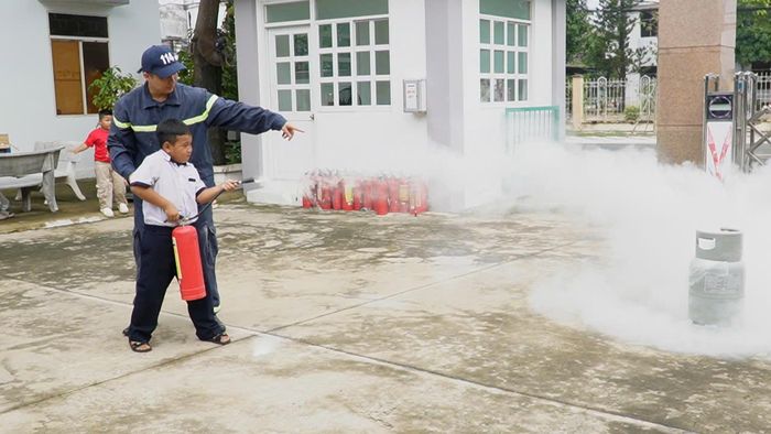 Tuyên truyền viên hướng dẫn các em nhỏ dùng bình chữa cháy