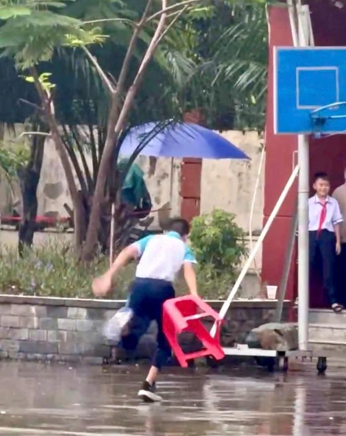 Hình ảnh một học sinh tại Thành phố Hồ Chí Minh đu trend bá khí khi trời mưa.