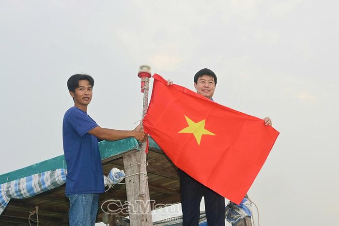 Đồng chí Lê Hải Long, Uỷ viên Ban Thường vụ, Trưởng Ban Công tác Thanh niên Trung ương Đoàn, treo cờ Tổ quốc cùng ngư dân trên tàu cá.