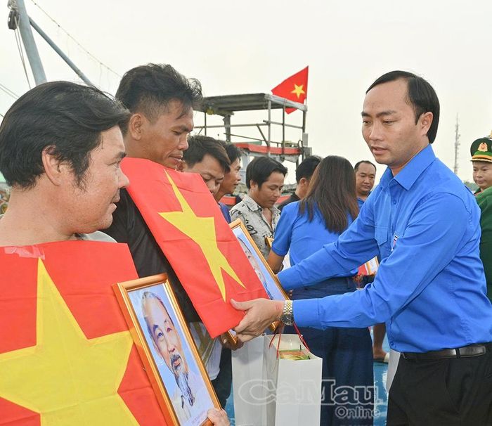 Đồng chí Phạm Tuấn Tài, Phó Chủ tịch Uỷ ban MTTQ Việt Nam tỉnh Cà Mau, Bí thư Tỉnh đoàn Cà Mau, trao cờ, ảnh Bác và quà cho các ngư dân.