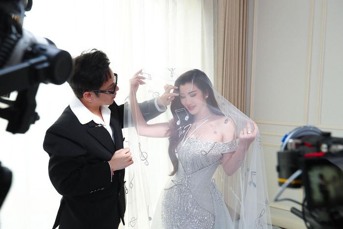 Trên lớp voan mỏng, Chung Thanh Phong đính Swarovski thành hình những nốt nhạc, thêu tên ca khúc “The Vow” - bản tình ca Châu Đăng Khoa viết lời để Akira Phan dành tặng vợ trong ngày cưới. Nhờ vậy, khăn voan không còn là phụ kiện che mặt cô dâu đơn thuần, mà trở thành kỷ vật mang thông điệp tỏ tình được chú rể gửi gắm khi hai người trở thành vợ chồng.