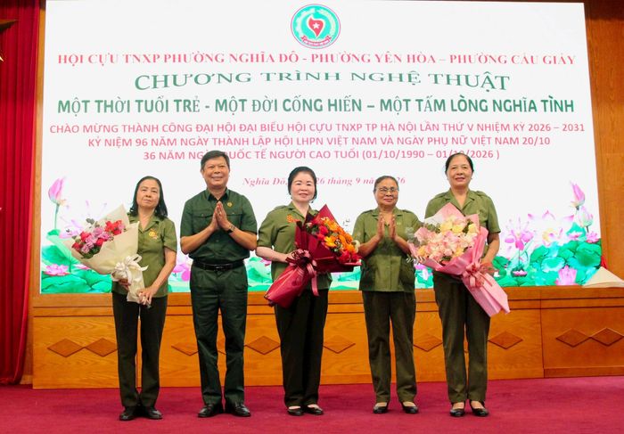 Chủ tịch Hội Cựu TNXP thành phố Hà Nội Lê Tuấn Hùng và Trưởng Ban Liên lạc Cựu TNXP khu vực Cầu Giấy Lê Thị Hồi tặng hoa 3 phường tham dự chương trình. Ảnh: Bảo Lâm