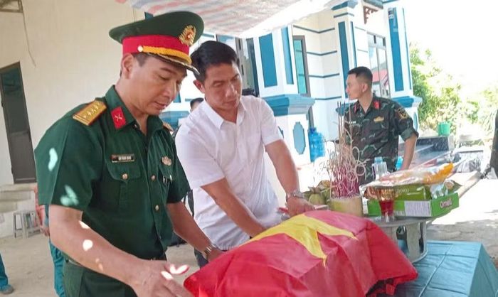 Thực hiện nghi thức phủ Quốc kỳ lên hài cốt của các Anh hùng liệt sĩ được tìm thấy ở bản Cang Kiểng, xã Chiềng Khoong. (Ảnh: THỌ SƠN)