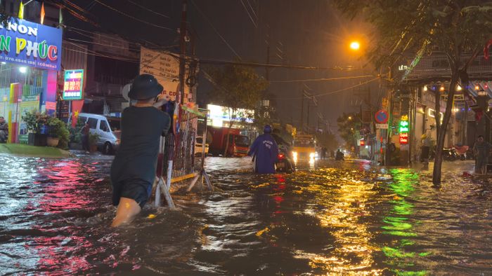 Lực lượng chức năng của địa phương hỗ trợ người dân dắt xe chết máy qua dòng nước ngập vào chiều tối 22-9. Ảnh: ĐÌNH DƯ