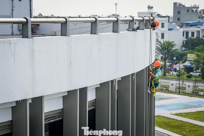 Công nhân đu dây kiểm tra lớp keo vách kính bên ngoài.