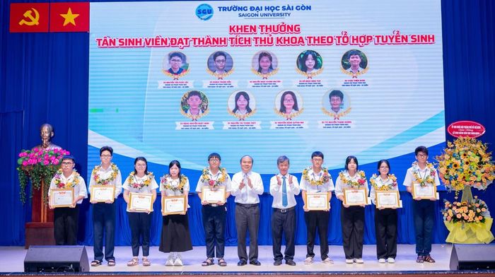 Ông Trần Văn Bảy - Phó Chủ tịch UBND TPHCM (thứ 6 từ trái sang) và PGS.TS Phạm Hoàng Quân - Hiệu trưởng Trường Đại học Sài Gòn (thứ 7 từ trái sang) trao khen thưởng, học bổng đến các thủ khoa.