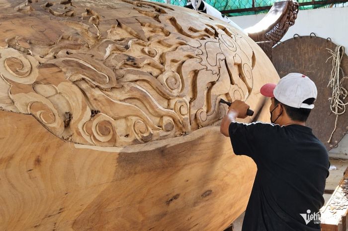 Người thợ chạm khắc hoa văn trên thân trống gỗ nguyên khối.