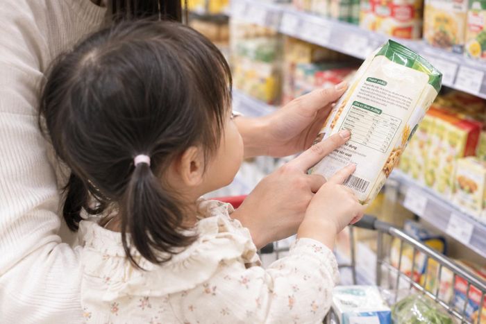 Khi trẻ bắt đầu biết đọc chữ, cha mẹ có thể hướng dẫn con nhận biết ngày sản xuất, hạn sử dụng và thành phần chính của sản phẩm. Ảnh: AI