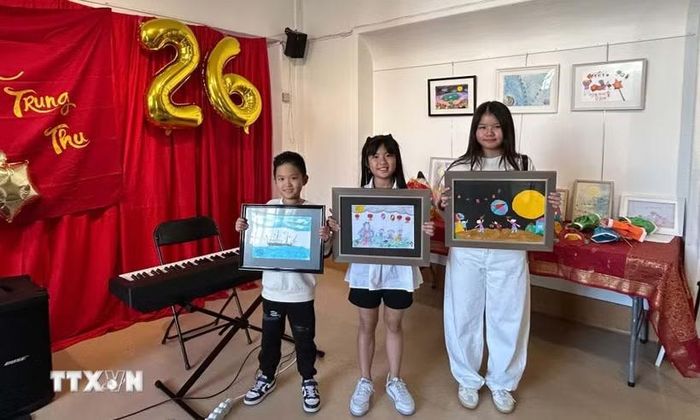 Em François Phạm, 8 tuổi (bên trái), cùng các thí sinh giới thiệu những tác phẩm tham dự cuộc thi vẽ tranh về Mặt Trăng. Bức tranh của François Phạm, khắc họa con tàu Việt Nam tuần tra trong đêm trăng rằm, đã giành giải Nhất nhờ thông điệp hướng về Trường Sa và những người lính đang ngày đêm gìn giữ biển, đảo quê hương. (Ảnh: Trần Đức Hùng/TTXVN)