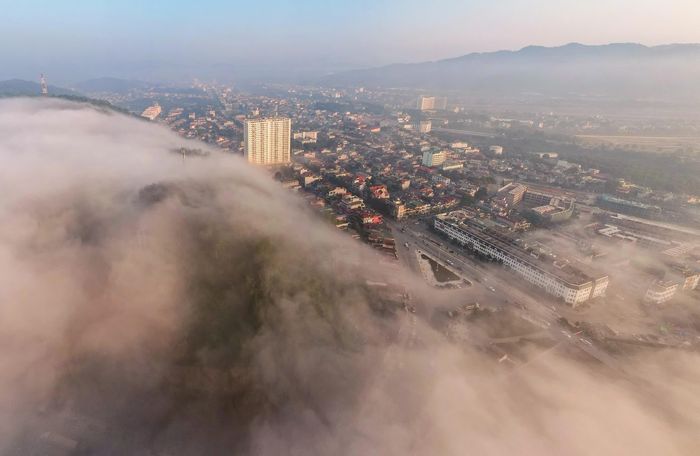 Dọc các tuyến phố, cảnh vật trở nên khác lạ. Những hàng cây, mái nhà và ánh đèn đường ẩn hiện trong làn sương sớm.