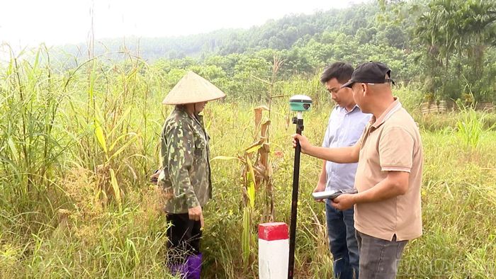 Người dân phối hợp với cán bộ đo đạc xác định mốc ranh giới và diện tích đất bị ảnh hưởng.