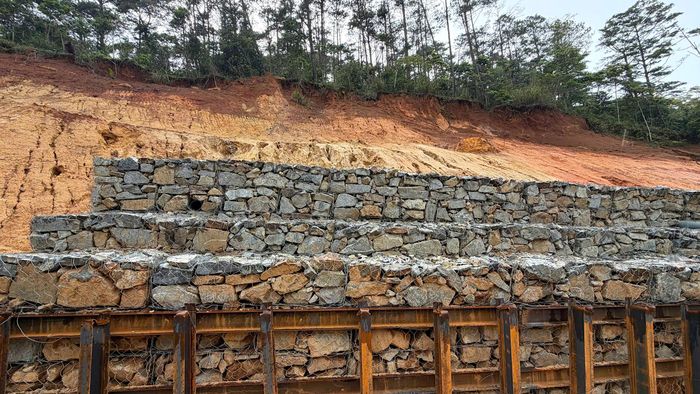 Theo thiết kế, tổng chiều dài vị trí khắc phục khoảng 320m. Trong đó, giải pháp là đào bỏ nền đường lún, trồi và phá bỏ tường chắn bê tông hư hỏng, bạt núi đào mái taluy sạt lở. Sau đó, thiết lập tường chắn rọ đá taluy dương kết hợp đóng cọc thép, thép giằng để giữ ổn định và bố trí tầng lọc, rãnh thoát nước ngầm, hoàn trả mặt đường nhựa, bố trí hệ thống ATGT.