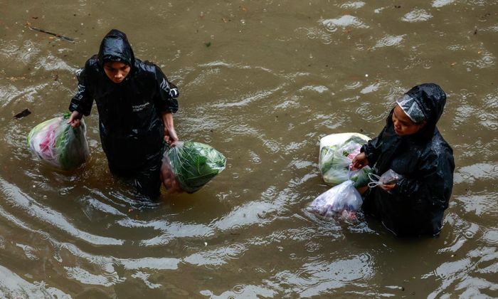 Người dân chật vật di chuyển trong dòng lũ - Ảnh: Reuters