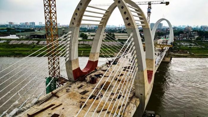 Cận cảnh trên mặt sàn nhịp chính, những người thợ vẫn miệt mài bám ca. Hơn 97% khối lượng vượt sông đã xong, công trường chuyển sang giai đoạn thi công lề bộ hành, căng kéo cáp dự ứng lực và chuẩn bị thảm bê tông nhựa.