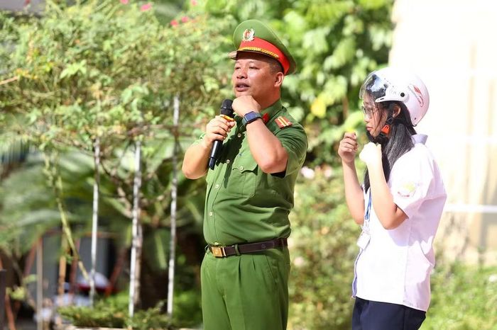 Học sinh thực hành cài dây mũ bảo hiểm đúng quy chuẩn dưới sự quan sát, hướng dẫn của báo cáo viên và thầy cô