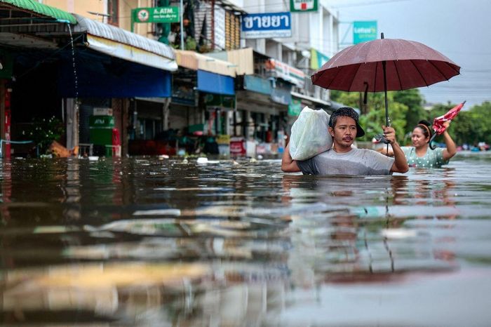  Một người dân Bangkok lội qua vùng ngập nhận đồ cứu trợ ngày 27/9. Ảnh: Patipat Janthong/Reuters. 