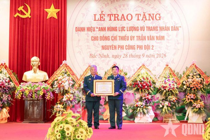  Thừa ủy quyền của Chủ tịch nước, Đại tá Nguyễn Như Khoát, Chính ủy Sư đoàn 371, trao danh hiệu Anh hùng LLVT nhân dân tặng phi công Trần Văn Năm (bên trái). 