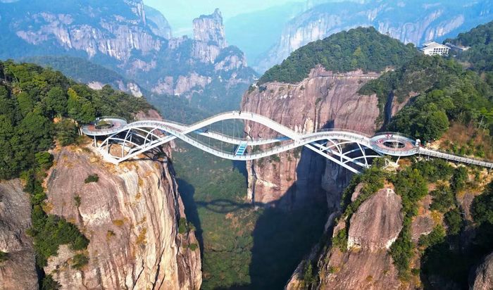 Điểm đặc biệt của công trình nằm ở cấu trúc gồm 3 mặt cầu uốn lượn, đan xen. Khi nhìn từ trên cao, toàn bộ cây cầu có hình dáng tựa một miếng ngọc Như Ý lơ lửng giữa không trung, cũng có nét tương đồng với dải lụa của một nàng tiên. Cầu được thiết kế bởi Hà Vân Xương - một trong những kiến trúc sư từng tham gia thiết kế sân vận động Tổ Chim ở Bắc Kinh. Ảnh: HighestBridges.com