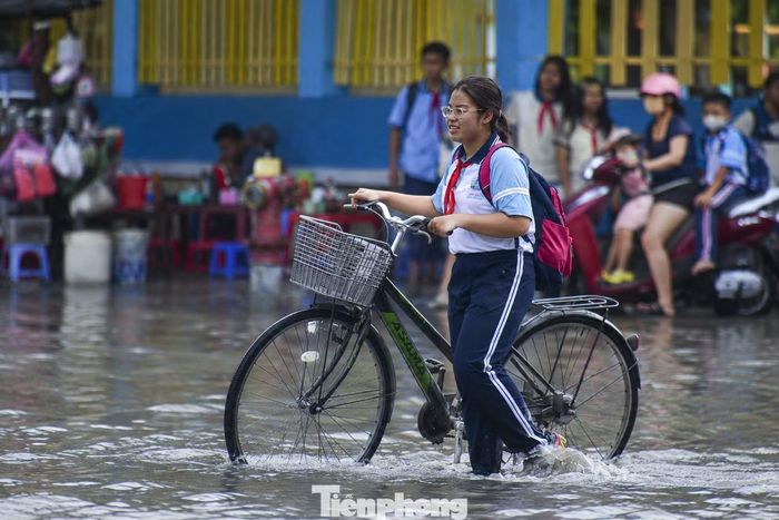 Học sinh, phụ huynh gặp khó khăn khi di chuyển qua đoạn đường ngập.