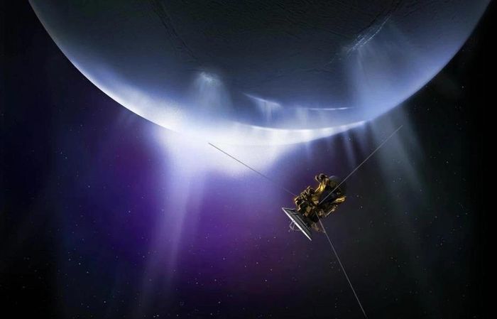 Hình ảnh mô phỏng tàu vũ trụ Cassini bay qua các luồng vật chất phun trào từ cực nam của Enceladus – một mặt trăng của sao Thổ. Các luồng phun này hoạt động tương tự như mạch nước phun, giải phóng hỗn hợp hơi nước, các hạt băng, muối, khí methane cùng những phân tử hữu cơ khác. Ảnh: NASA/JPL-Caltech