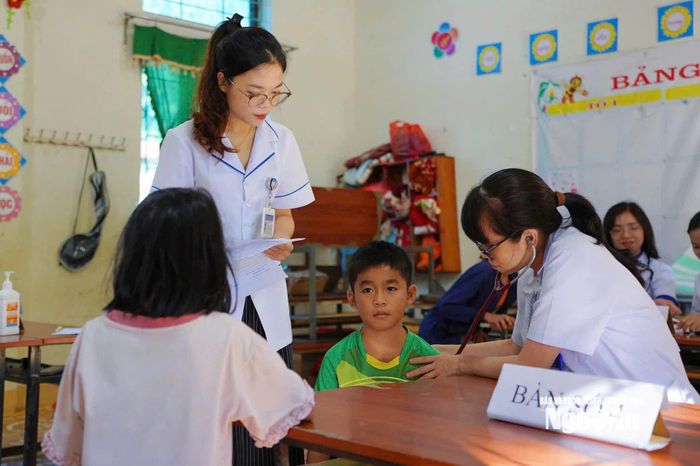 Các y, bác sỹ kiểm tra sức khỏe cho các em học sinh.