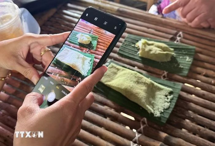 Du khách thích thú chụp ảnh những chiếc bánh rây vừa được chế biến. (Ảnh: Thanh Sang/TTXVN)