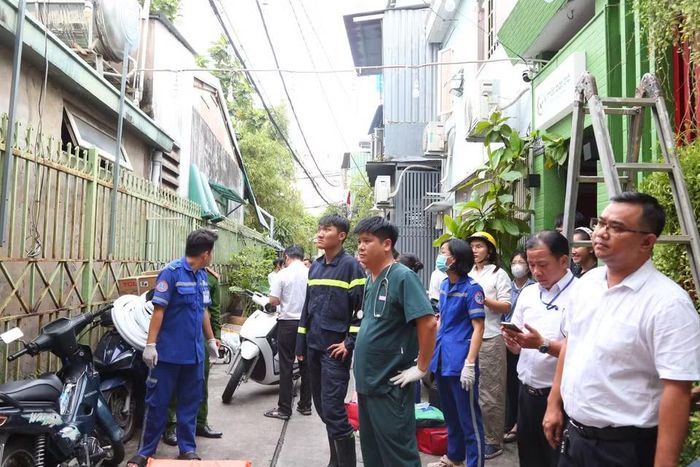 Người dân đứng theo dõi lực lượng chức năng làm nhiệm vụ giải cứu người mắc kẹt. (Ảnh: PV/Vietnam+)