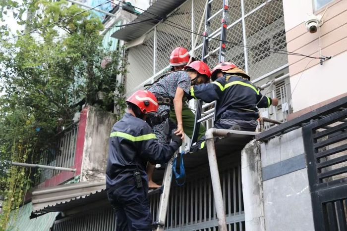 Lực lượng chức năng đưa hai nạn nhân ở trên gác bị mắc kẹt ra ngoài an toàn. (Ảnh: PV/Vietnam+)