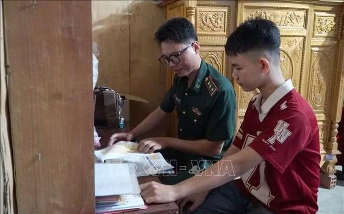 Em Trần Quang Hiếu (bên phải) thường xuyên được cán bộ, chiến sĩ Đồn Biên phòng Tam Thanh động viên học tập, giúp định hướng trong tương lai. Ảnh: Quốc Dũng/TTXVN
