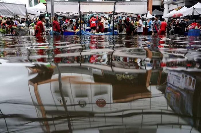 Người dân di chuyển qua một khu chợ ngập nước ở Bangkok, Thái Lan. Ảnh: Reuters.