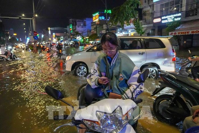 Tan ca từ 17 giờ 30, em Nguyễn Ngọc Tú vẫn đỗ xe trên đường Nguyễn Văn Cừ chờ nước rút để về nhà ở Cồn Khương lúc hơn 19 giờ. Ảnh: Thanh Liêm - TTXVN 