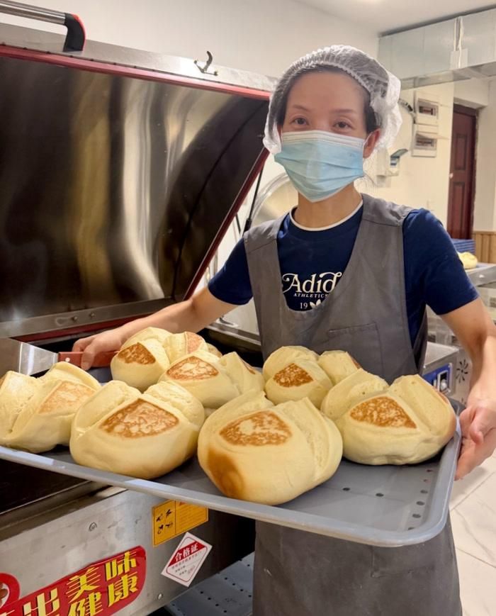 Đông Mẫn bưng một đĩa bánh màn thầu sữa vừa mới ra lò. Ảnh: Changjiang Daily