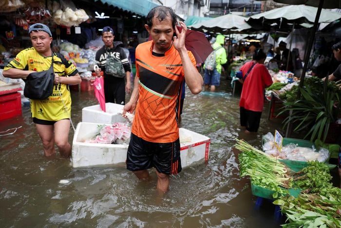  Người dân di chuyển qua vùng nước dâng cao tại một khu chợ. (Ảnh: Reuters)