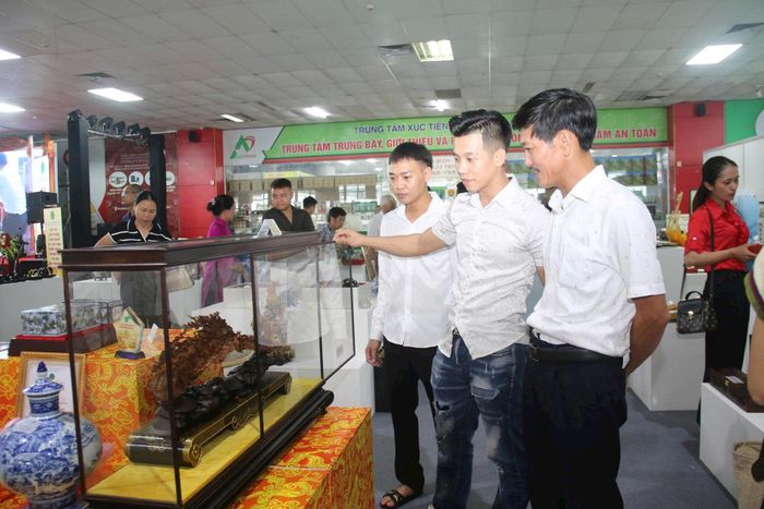 Anh Đào Đình Sáng, tác giả đạt giải nhất (đứng giữa) giới thiệu với khách tham quan sản phẩm dự thi được giải nhất "Phu thê viên mãn" trưng bày tại Hội thi.