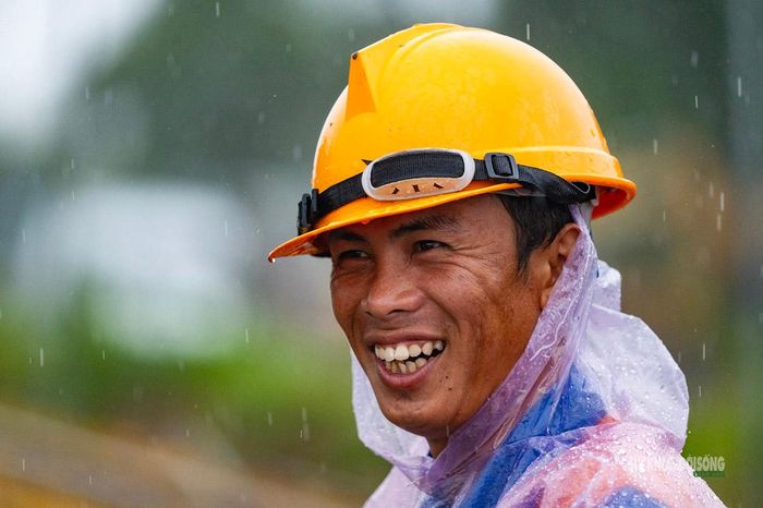Nụ cười của người thợ giữa ca làm việc dưới mưa. Ảnh: Hoàng Hà.