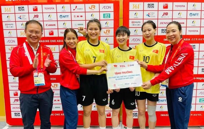 Trưởng đoàn Việt Nam Nguyễn Hồng Minh (trái) thưởng "nóng" tấm huy chương Vàng đôi nữ môn cầu mây (Ảnh: Bùi Lượng)