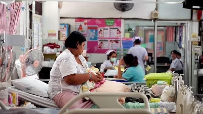  Một người phụ nữ đang bế một em bé sơ sinh trong một bệnh viện ở Thái Lan. 