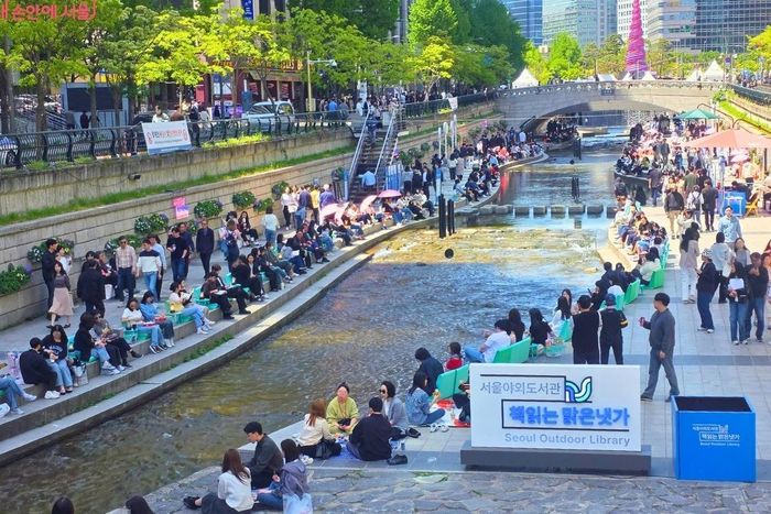 Hàng trăm người đọc sách, thư giãn tại thư viện ngoài trời bên suối Cheonggyecheon ở Seoul (Hàn Quốc). Ảnh: Chính quyền Seoul.
