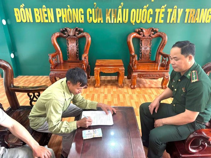Anh Trần Công Trí (ở thôn Tân Ngam, xã Núa Ngam, tỉnh Điện Biên) ký biên bản nhận lại số tiền đánh rơi trước sự chứng kiến của Thiếu tá Nông Văn Thiết và lãnh đạo chỉ huy Đồn Biên phòng Cửa khẩu quốc tế Tây Trang. (Ảnh: LÊ LAN)