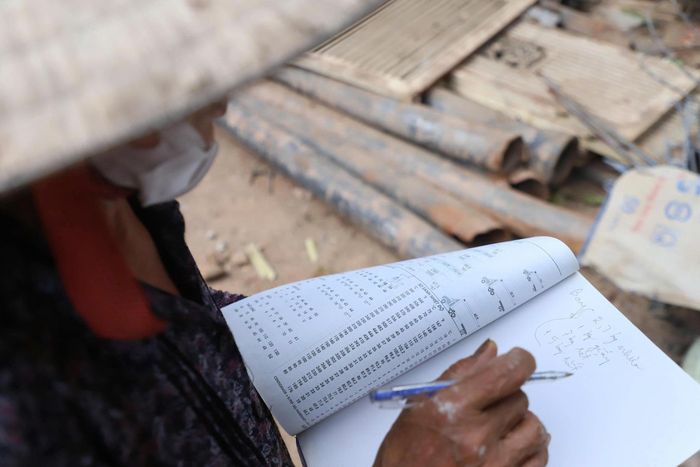 Bà Hoa ghi chép thu nhập sau một ngày lao động vất vả. Ảnh: TIẾN CƯỜNG