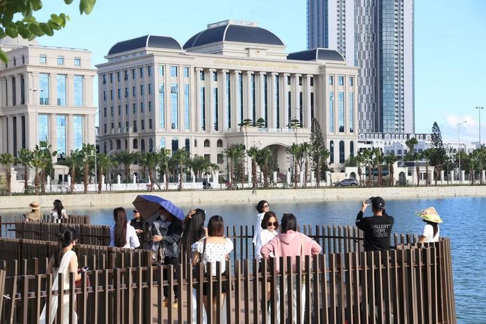 Từ phía bên kia hồ, hai trụ sở nằm gần như trọn vẹn trong một khung hình﻿. Mặt nước tạo khoảng cách vừa đủ để những tòa nhà lớn không bị choán hết khung ảnh, trong khi sàn gỗ sát hồ trở thành vị trí đứng chụp thuận tiện. 