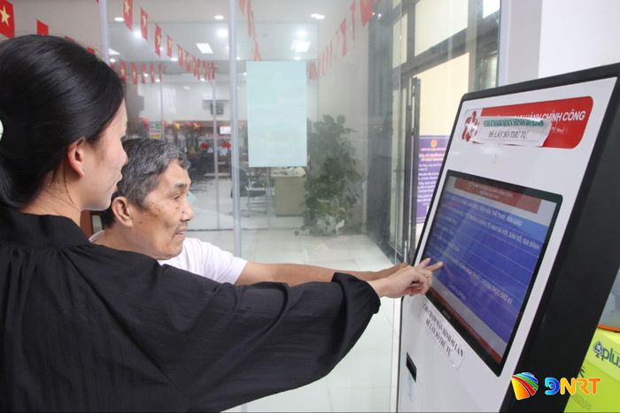 Cán bộ hỗ trợ người dân giao dịch trực tuyến. Ảnh: HÀN NGUYÊN