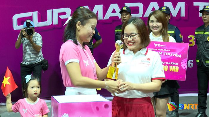 Madam Truyền trao chiếc cup và bảng số tiền tượng trưng đến Ban tổ chức trong lễ khai mạc.